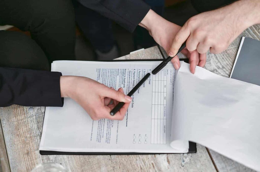 A woman holding a pen over a document A woman filling out a document