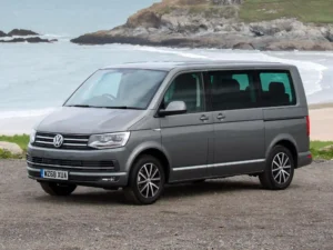 Сірий Volkswagen Caravelle Family біля узбережжя, вигляд спереду збоку