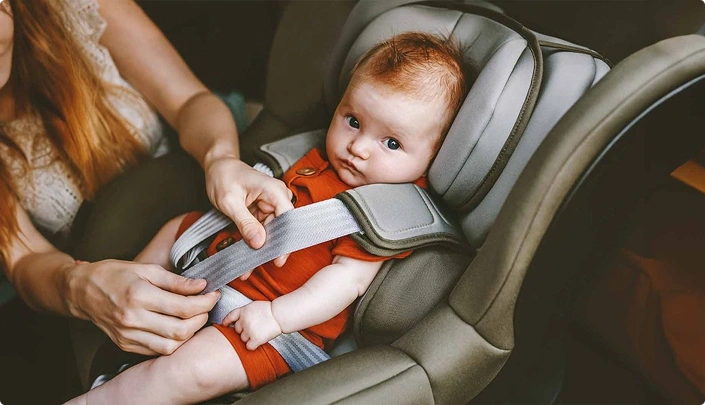 Мати пристібає дитину в автокріслі перед поїздкою - mytaxitransfer24