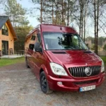 Червоний Mercedes Benz Sprinter на фоні заміського пейзажа
