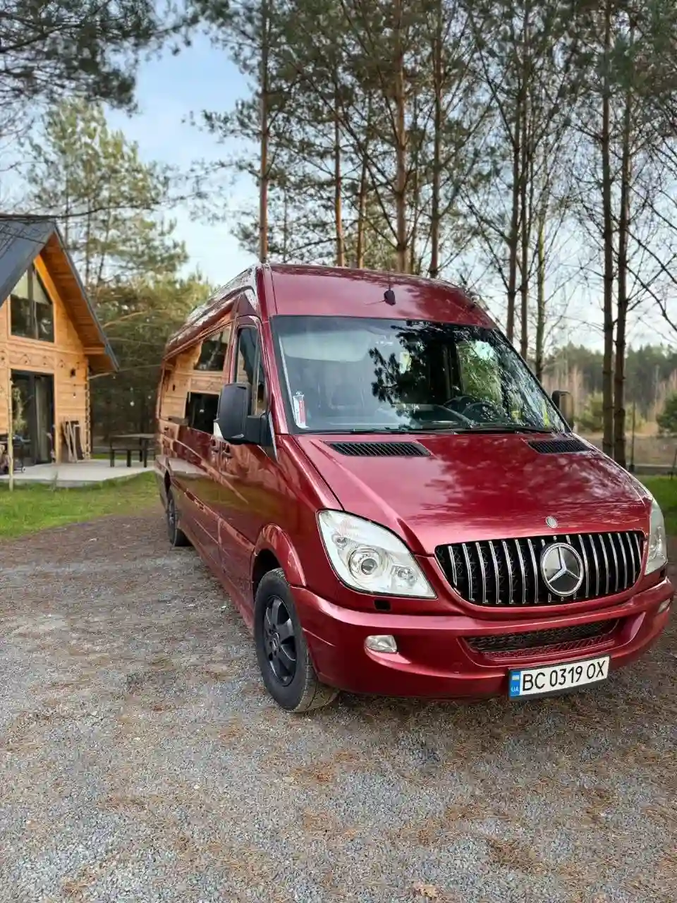 Червоний Mercedes Benz Sprinter на фоні заміського пейзажа