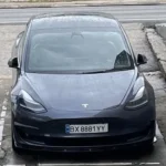 Передній вигляд автомобіля Tesla, що їде міською вулицею