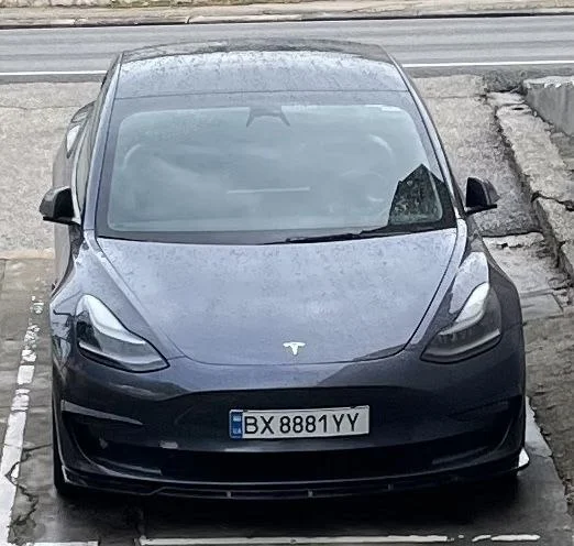 Передній вигляд автомобіля Tesla, що їде міською вулицею